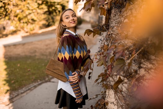 Pretty young woman standing outside at sunny autumn day