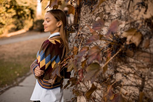 Pretty young woman standing outside at sunny autumn day