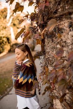 Pretty young woman standing outside at sunny autumn day