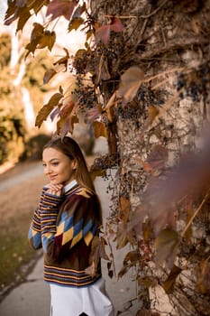 Pretty young woman standing outside at sunny autumn day