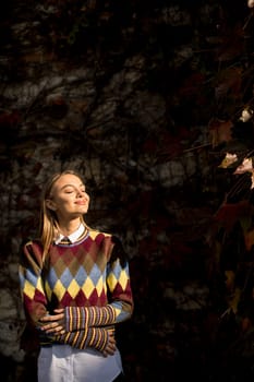 Pretty young woman standing outside at sunny autumn day