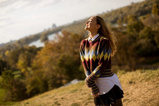 Pretty young woman standing outside at sunny autumn day