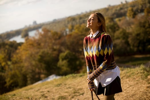 Pretty young woman standing outside at sunny autumn day