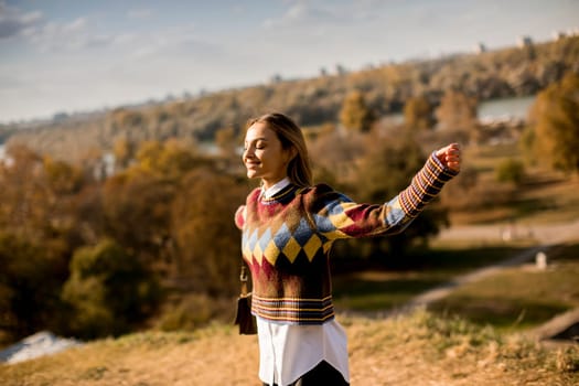Pretty young woman walking outside at sunny autumn day