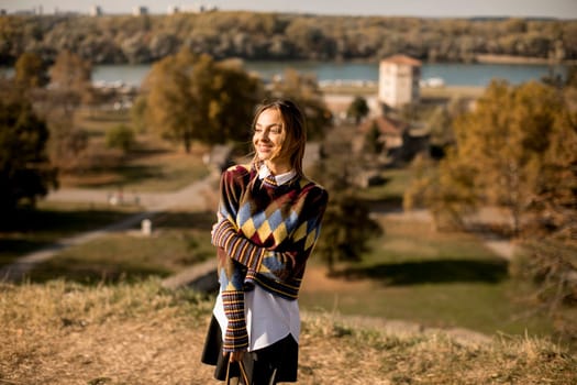 Pretty young woman standing outside at sunny autumn day
