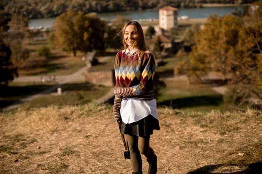 Pretty young woman standing outside at sunny autumn day