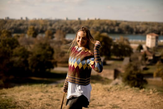 Pretty young woman standing outside at sunny autumn day