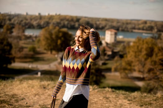 Pretty young woman standing outside at sunny autumn day