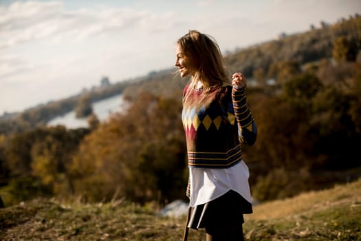 Pretty young woman standing outside at sunny autumn day