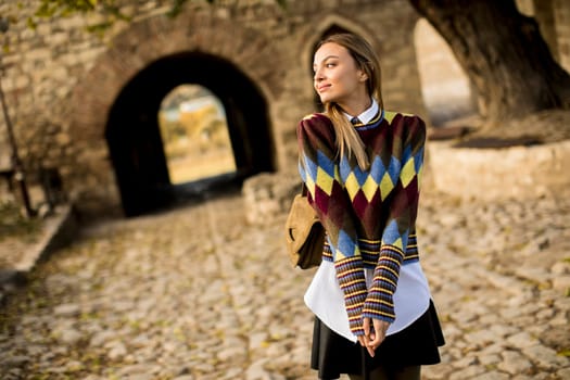 Pretty young woman standing outside at sunny autumn day