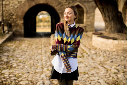 Pretty young woman standing outside at sunny autumn day