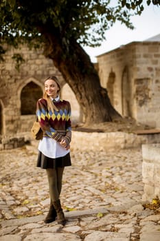 Pretty young woman standing outside at sunny autumn day