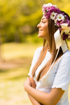 Pretty young woman with flowers in her hair on sunny spring day
