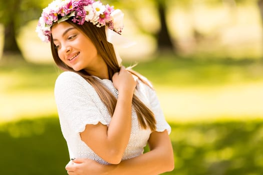 Pretty young woman with flowers in her hair on sunny spring day