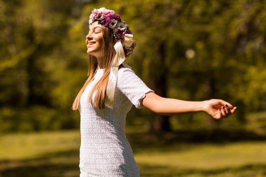 Pretty young woman with flowers in her hair on sunny spring day
