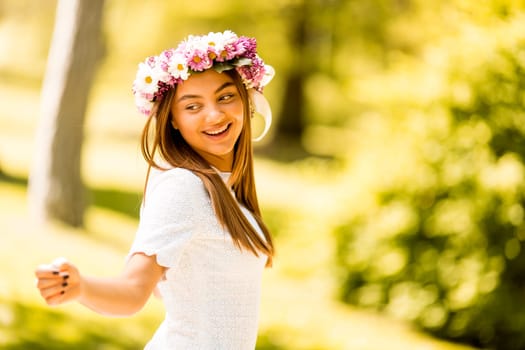 Pretty young woman with flowers in her hair on sunny spring day