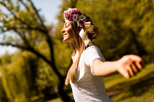 Pretty young woman with flowers in her hair on sunny spring day