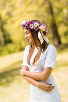 Pretty young woman with flowers in her hair on sunny spring day
