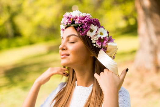 Pretty young woman with flowers in her hair on sunny spring day