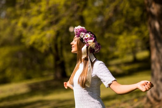 Pretty young woman with flowers in her hair on sunny spring day