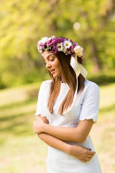 Pretty young woman with flowers in her hair on sunny spring day