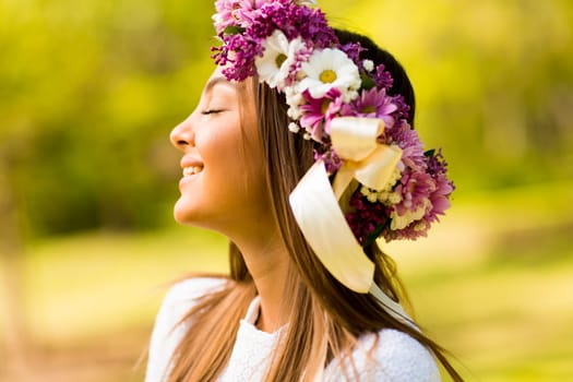 Pretty young woman with flowers in her hair on sunny spring day