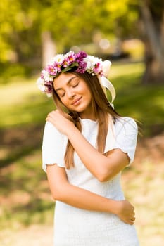 Pretty young woman with flowers in her hair on sunny spring day
