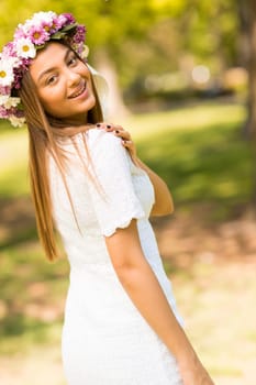 Pretty young woman with flowers in her hair on sunny spring day