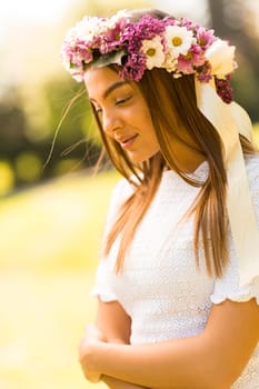 Pretty young woman with flowers in her hair on sunny spring day
