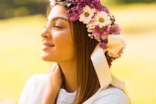 Pretty young woman with flowers in her hair on sunny spring day