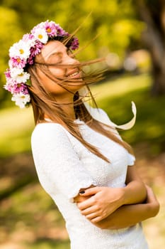 Pretty young woman with flowers in her hair on sunny spring day