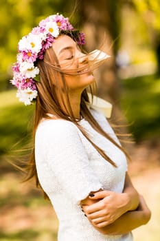Pretty young woman with flowers in her hair on sunny spring day