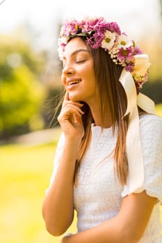 Pretty young woman with flowers in her hair on sunny spring day