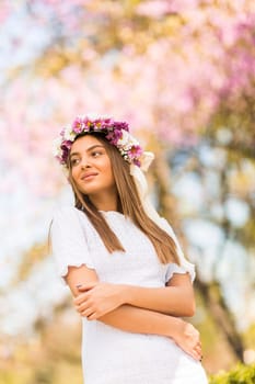 Pretty young woman with flowers in her hair on sunny spring day