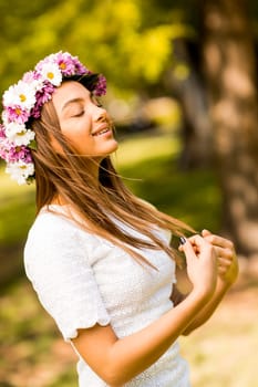 Pretty young woman with flowers in her hair on sunny spring day