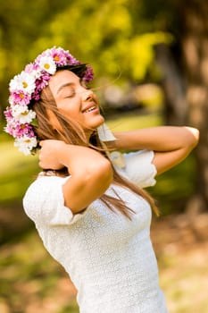 Pretty young woman with flowers in her hair on sunny spring day