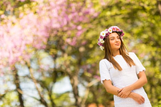 Pretty young woman with flowers in her hair on sunny spring day