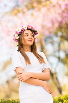 Pretty young woman with flowers in her hair on sunny spring day