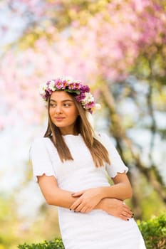 Pretty young woman with flowers in her hair on sunny spring day