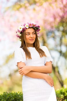 Pretty young woman with flowers in her hair on sunny spring day