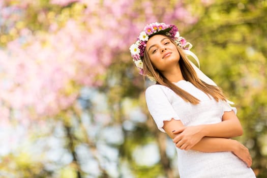 Pretty young woman with flowers in her hair on sunny spring day