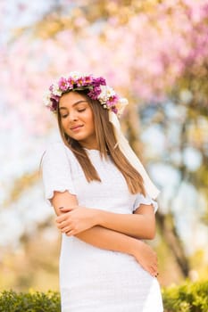 Pretty young woman with flowers in her hair on sunny spring day