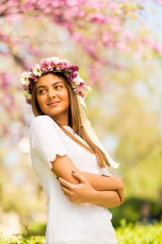 Pretty young woman with flowers in her hair on sunny spring day
