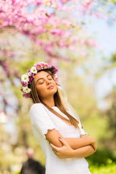 Pretty young woman with flowers in her hair on sunny spring day