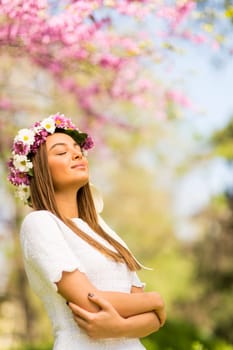 Pretty young woman with flowers in her hair on sunny spring day