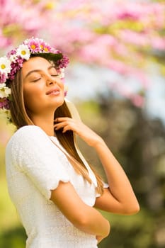 Pretty young woman with flowers in her hair on sunny spring day