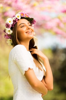 Pretty young woman with flowers in her hair on sunny spring day