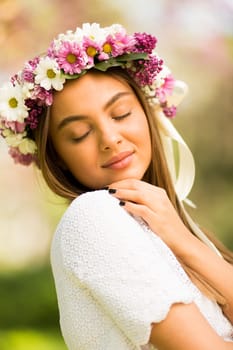 Pretty young woman with flowers in her hair on sunny spring day