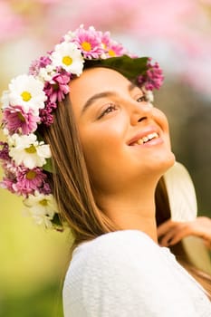 Pretty young woman with flowers in her hair on sunny spring day