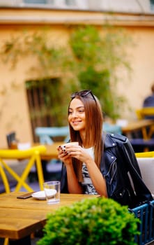 Pretty young woman drinking coffee in cafe on a sunny day